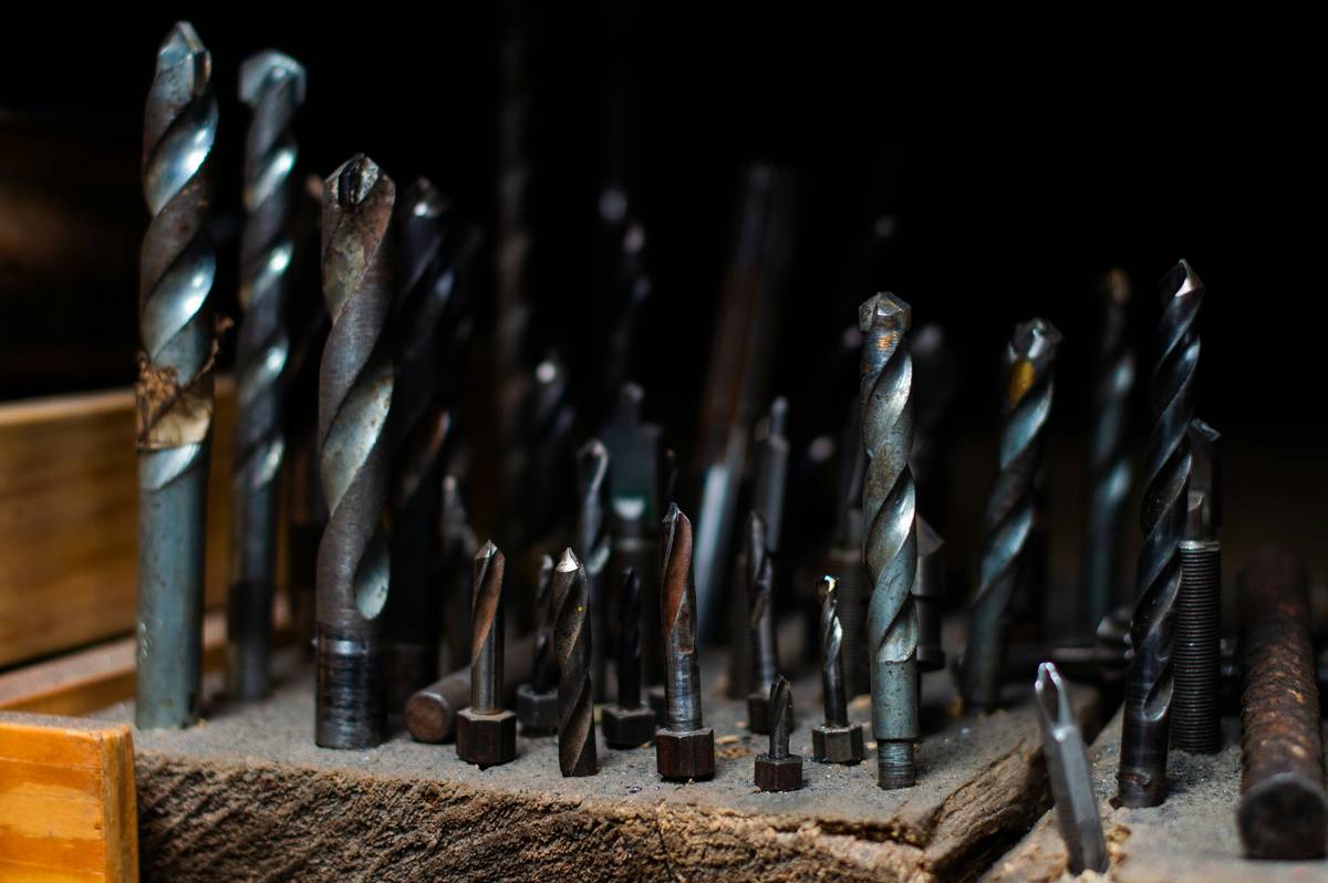 Infographic showing effects of poor vs. proper drill bit storage: rust, chipping, and tip deformation on left; clean, labeled bits in organized box on right
